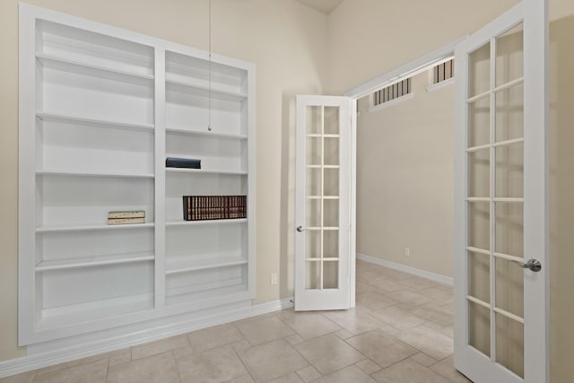 empty room featuring french doors, baseboards, and built in shelves