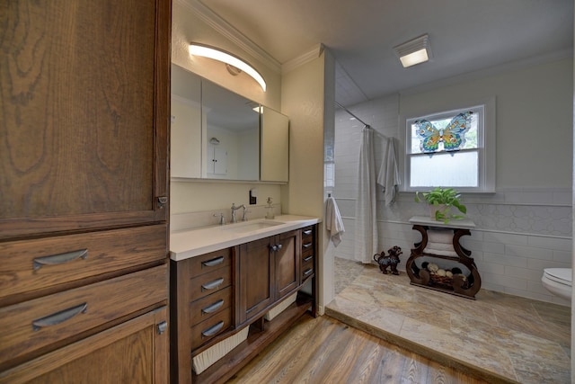 full bathroom featuring a shower with curtain, toilet, tile walls, crown molding, and vanity
