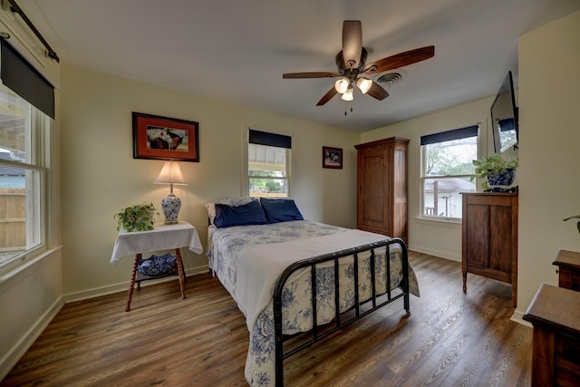 bedroom featuring wood finished floors, baseboards, and multiple windows