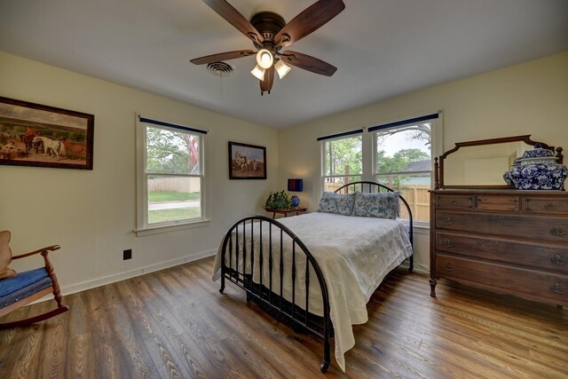 bedroom with wood finished floors, baseboards, and multiple windows