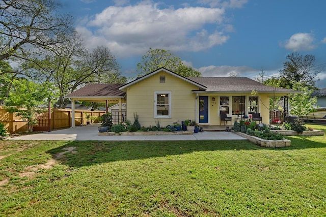back of house featuring fence, covered porch, an attached carport, and a yard
