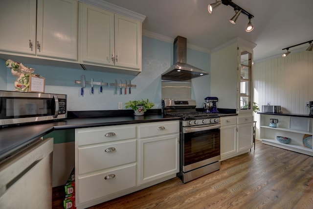 kitchen featuring dark countertops, light wood-style floors, stainless steel appliances, wall chimney exhaust hood, and white cabinetry