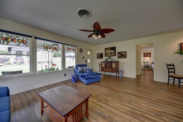living area with wood finished floors, visible vents, baseboards, and ceiling fan