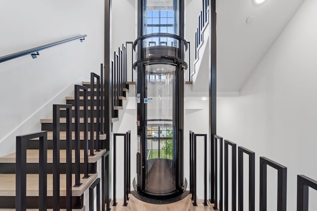 stairs featuring a high ceiling, plenty of natural light, and wood finished floors