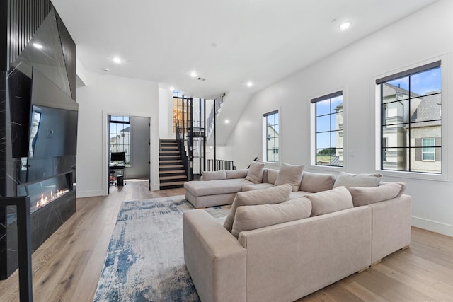living room featuring stairs, recessed lighting, baseboards, and light wood finished floors