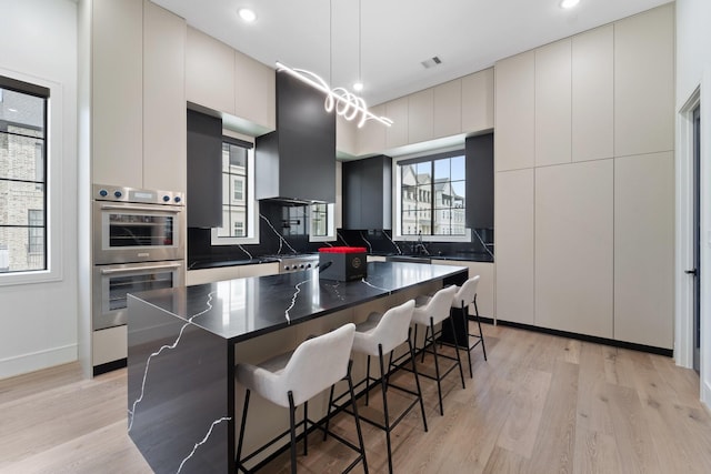 948 Blackshire Ln, Houston, TX 77055 - kitchen with double oven, dark countertops, modern cabinets, a breakfast bar, and light wood-type flooring