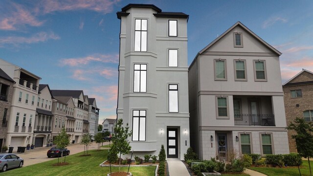 view of front of home with a residential view, a front yard, and stucco siding