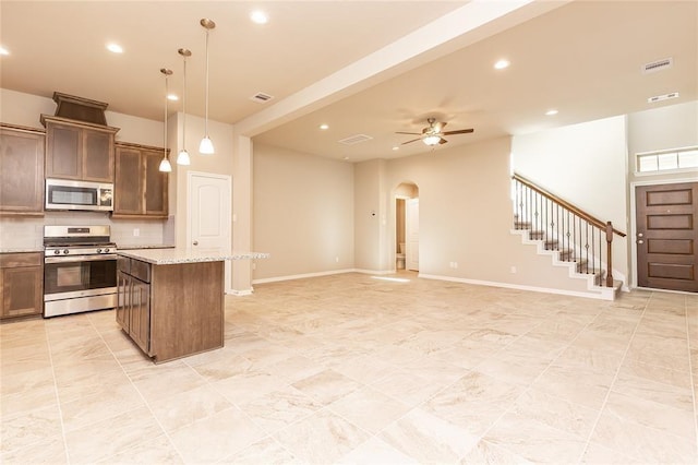 5546 Sallow Bay Ln, Fulshear, TX 77441 - kitchen with a center island, arched walkways, recessed lighting, backsplash, and appliances with stainless steel finishes