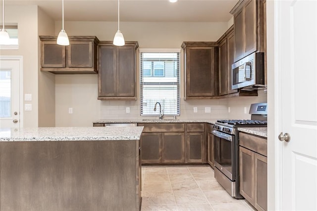 5546 Sallow Bay Ln, Fulshear, TX 77441 - kitchen with light stone counters, tasteful backsplash, a sink, dark brown cabinetry, and appliances with stainless steel finishes