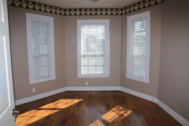 spare room featuring baseboards, a healthy amount of sunlight, and hardwood / wood-style floors