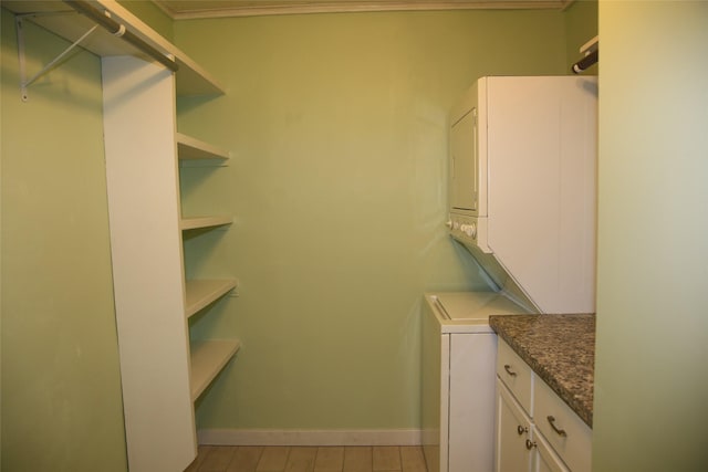 laundry room with baseboards and stacked washer / dryer