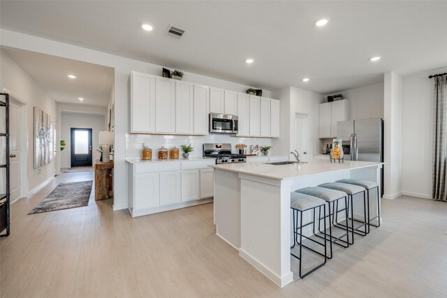406 Robin St, Angleton, TX 77515 - kitchen featuring appliances with stainless steel finishes, a breakfast bar, light wood-style floors, a sink, and recessed lighting