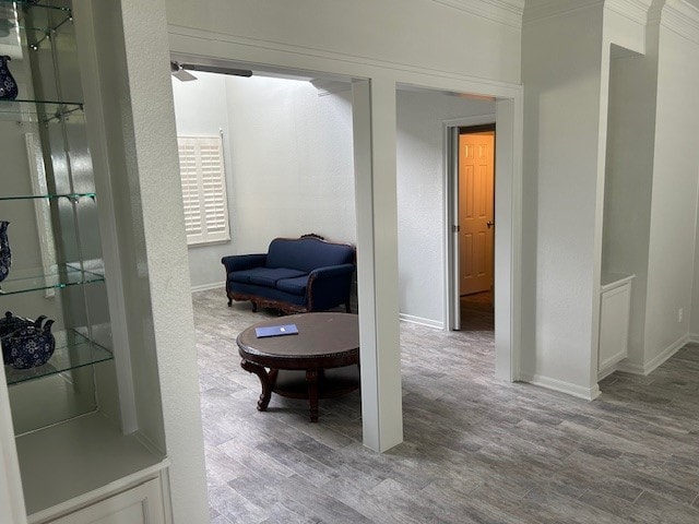 sitting room with crown molding, ceiling fan, baseboards, and wood finished floors