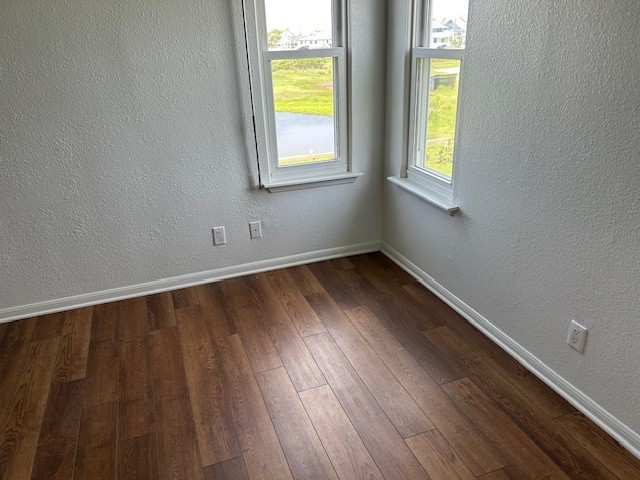 spare room with baseboards, dark wood-style flooring, and a textured wall