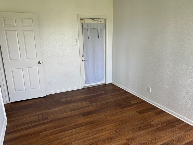 unfurnished bedroom with dark wood-style flooring, baseboards, and a closet