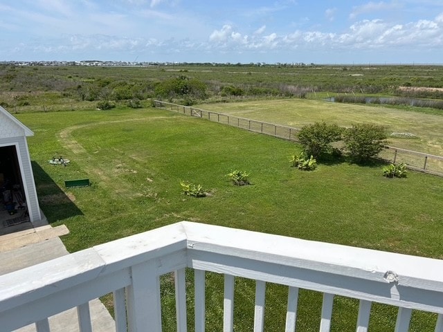 view of yard with fence, a balcony, and a rural view