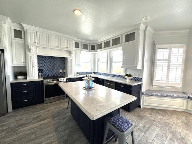 12924 Stewart Rd, Galveston, TX 77554 - kitchen featuring stainless steel appliances, a breakfast bar, dark cabinets, decorative backsplash, and white cabinetry