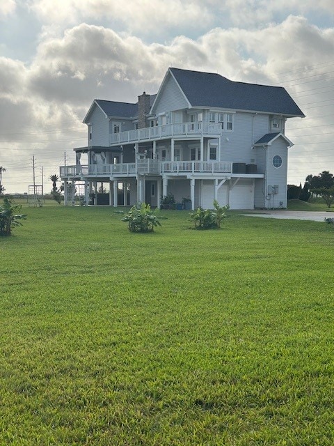 12924 Stewart Rd, Galveston, TX 77554 - rear view of property with a yard, a garage, and a balcony