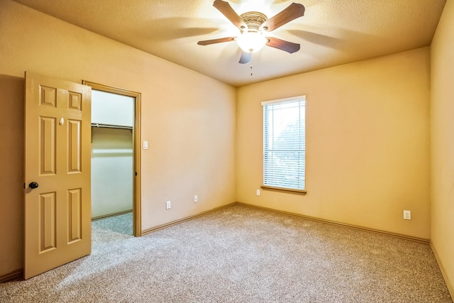 carpeted spare room with baseboards, a ceiling fan, and a textured ceiling