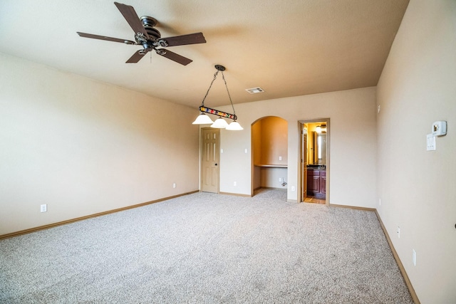 unfurnished room featuring a ceiling fan, arched walkways, light colored carpet, baseboards, and visible vents