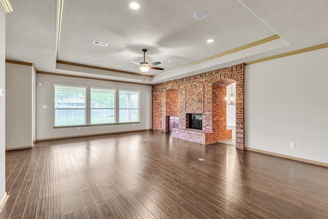 unfurnished living room featuring visible vents, a ceiling fan, a tray ceiling, and a brick fireplace
