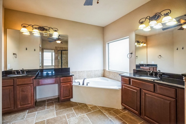 full bathroom with a shower stall, a sink, stone tile flooring, a garden tub, and ceiling fan