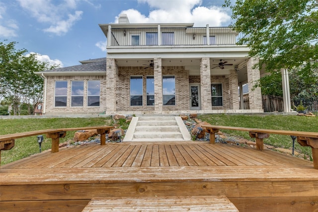 back of property with ceiling fan, a wooden deck, a balcony, a chimney, and brick siding