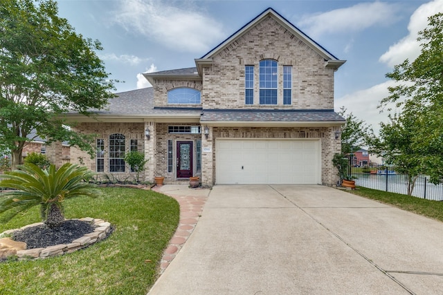 traditional-style home with a garage, fence, a front yard, brick siding, and concrete driveway