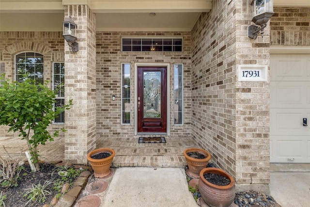 doorway to property with covered porch and brick siding