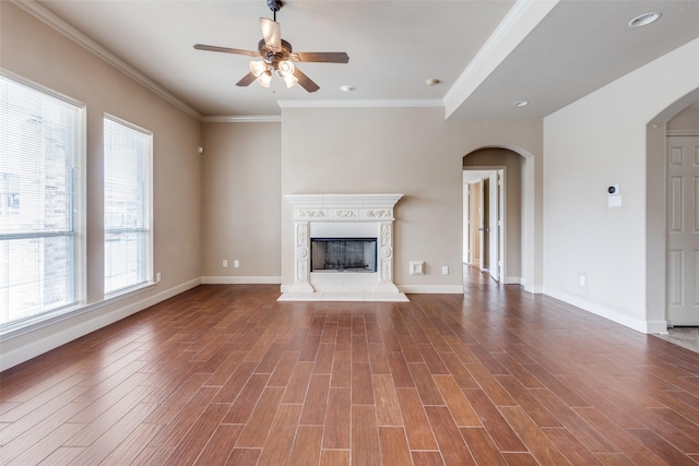 unfurnished living room with baseboards, a ceiling fan, arched walkways, and wood finished floors