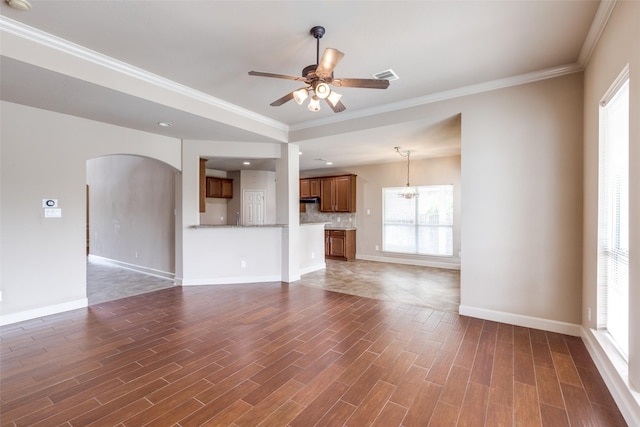 unfurnished living room featuring baseboards, a ceiling fan, wood finished floors, and ornamental molding
