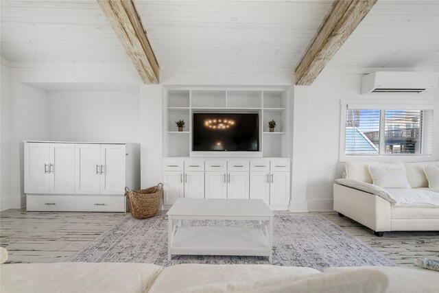 living room featuring light wood-style flooring, a wall mounted AC, beamed ceiling, and baseboards