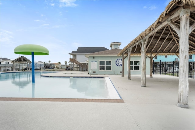 community pool with fence, a gazebo, and a patio