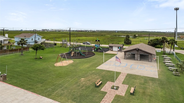 view of property's community with a lawn, fence, playground community, and a detached garage
