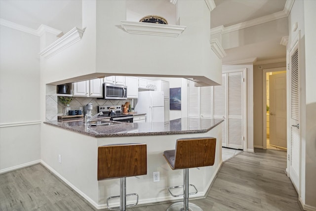 2111 Welch St Unit A219, Houston, TX 77019 - kitchen with light wood finished floors, stainless steel appliances, a peninsula, dark stone counters, and backsplash