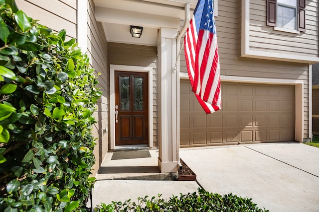view of exterior entry featuring an attached garage and concrete driveway