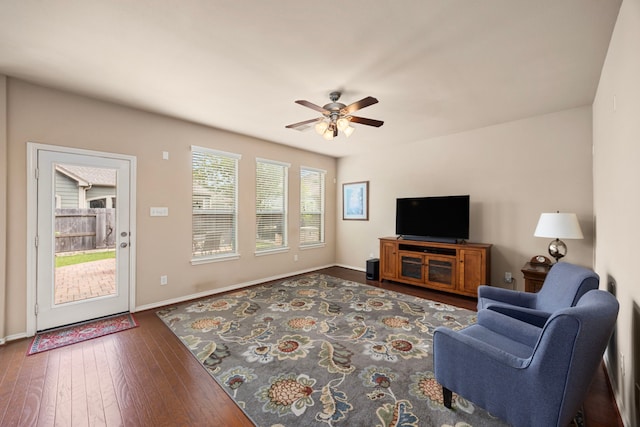 living area with ceiling fan, baseboards, and dark wood-style floors