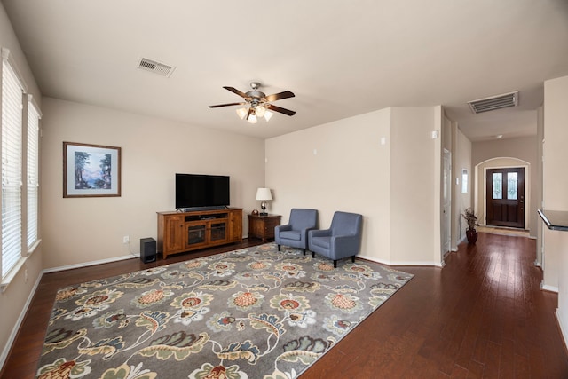 living area featuring ceiling fan, arched walkways, wood finished floors, and visible vents