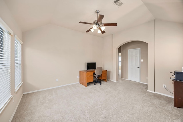 unfurnished office with carpet, vaulted ceiling, visible vents, and arched walkways