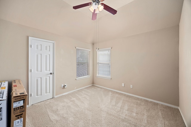unfurnished bedroom with lofted ceiling, a ceiling fan, baseboards, and light colored carpet