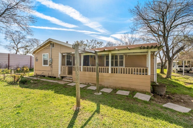 rear view of property with a yard and a sunroom