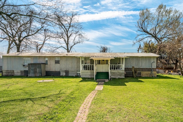 rear view of property featuring a yard and metal roof