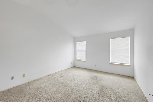 empty room featuring light colored carpet and lofted ceiling