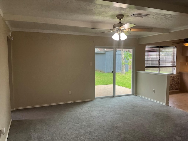 carpeted spare room featuring a textured ceiling, baseboards, visible vents, beamed ceiling, and a ceiling fan