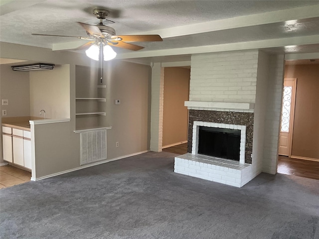 unfurnished living room featuring carpet, visible vents, a fireplace, a textured ceiling, and ceiling fan