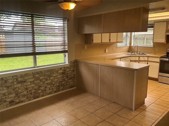 kitchen featuring a sink, light tile patterned flooring, stainless steel range with electric cooktop, ceiling fan, and light countertops