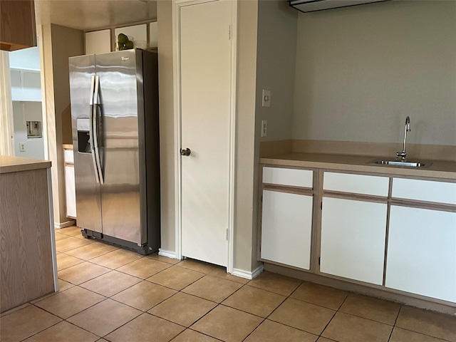 kitchen featuring light countertops, stainless steel fridge, light tile patterned floors, and a sink