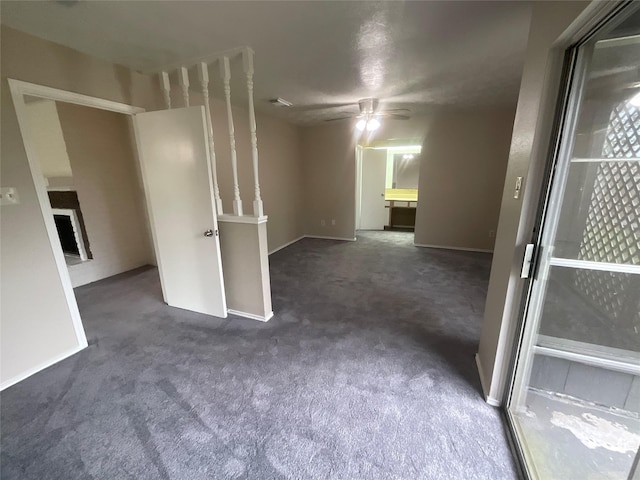 empty room featuring baseboards, dark carpet, and ceiling fan