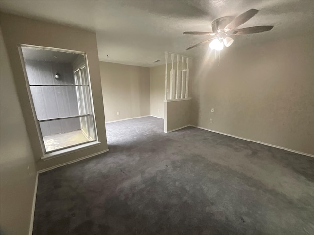spare room featuring dark carpet, baseboards, and ceiling fan