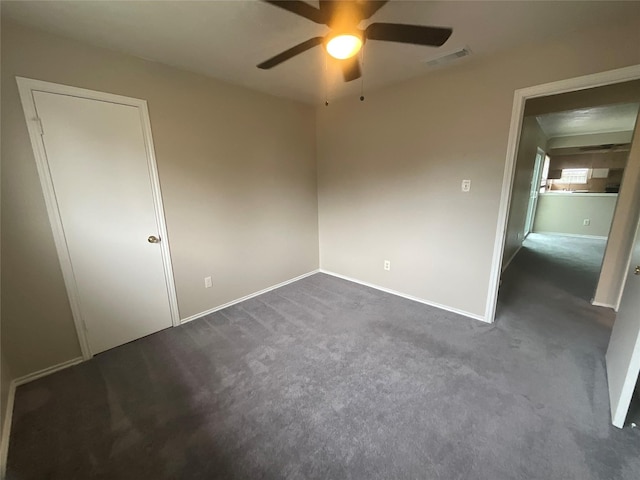 unfurnished bedroom with ceiling fan, baseboards, dark colored carpet, and visible vents